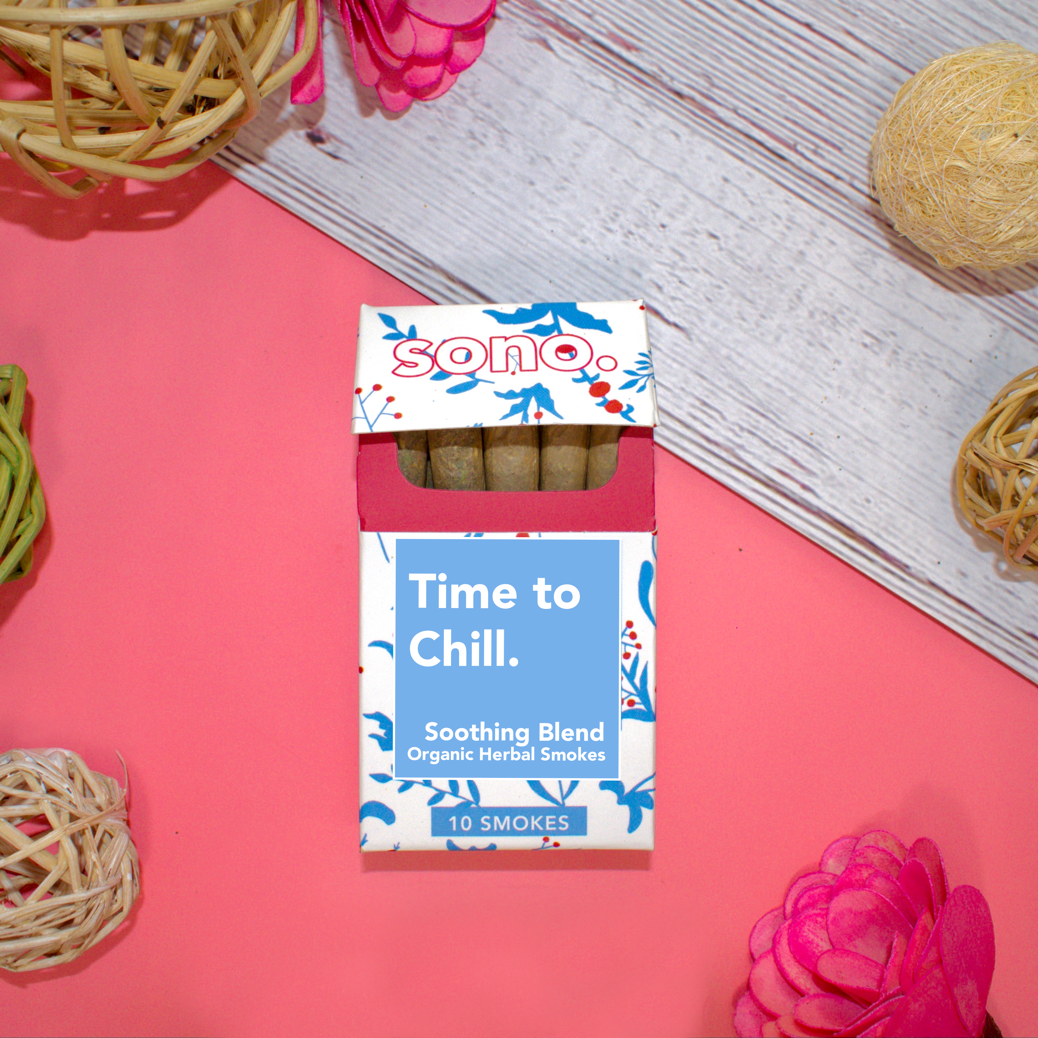 Image Description: A cardboard smoke pack titled Time to Chill, referring to the herbal smoking blend that the 10 smokes inside are filled with. Beneath the title are the words Soothing Blends, & Organic Herbal Smokes. The box is decorated with blue floral shapes designed to look like the ingredients inside: Marigold, Klip Dagga, Rosemary, Mullein, Skullcap & Lavender. Peeking out from the pack are 10 herbal prerolls, also known as Herbal Spliffs, Herbal Cigarettes, Herbs & Flowers Prerolls, or Herb Tokes.