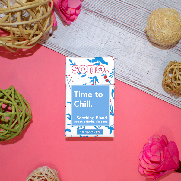 Image Description: A cardboard smoke pack titled Time to Chill, an herbal smoking blend offered for sale by a trans woman owned herbal apothecary, Sono Herbs. The cigarette box is white & made with recycled paper and eco-friendly materials. There are blue designs on the white box, silhouettes of the herbs and flowers which are ingredients: Marigold, Klip Dagga, Rosemary, Mullein, Skullcap & Lavender.  Herbal smokes are also known as Herbal Spliffs, Herbal Cigarettes, Herbs & Flowers Prerolls, or Herb Tokes.