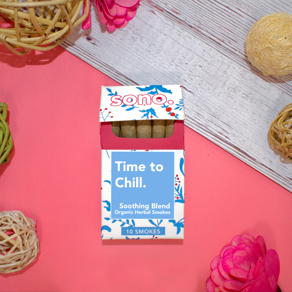 Image Description: A cardboard smoke pack titled Time to Chill, referring to the herbal smoking blend that the 10 smokes inside are filled with. Beneath the title are the words Soothing Blends, & Organic Herbal Smokes. The box is decorated with blue floral shapes designed to look like the ingredients inside: Marigold, Klip Dagga, Rosemary, Mullein, Skullcap & Lavender. Peeking out from the pack are 10 herbal prerolls, also known as Herbal Spliffs, Herbal Cigarettes, Herbs & Flowers Prerolls, or Herb Tokes.